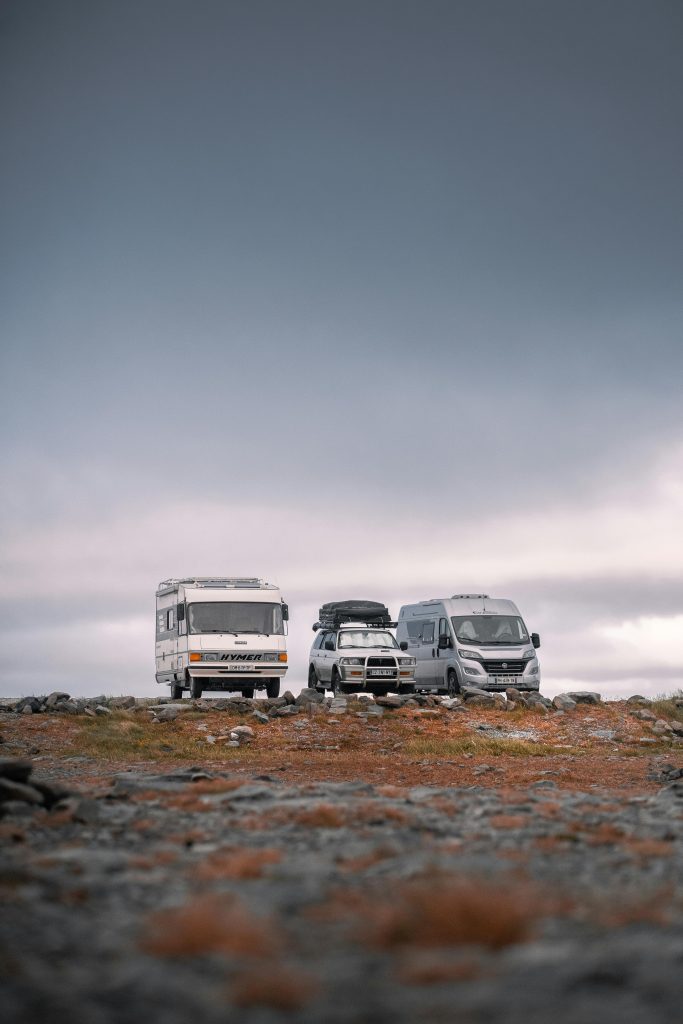 Two caravans and leisure vehicles parked on the horizon at dusk under a soft evening sky.